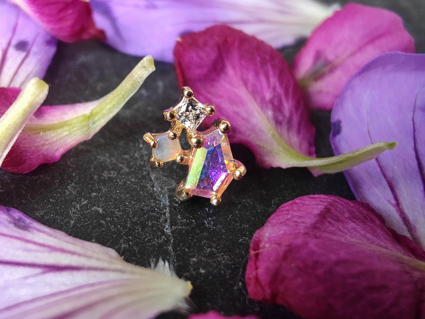 3 stones of different sizes connected by a gold setting. one in mercury mist topaz, one opal and one white cz.