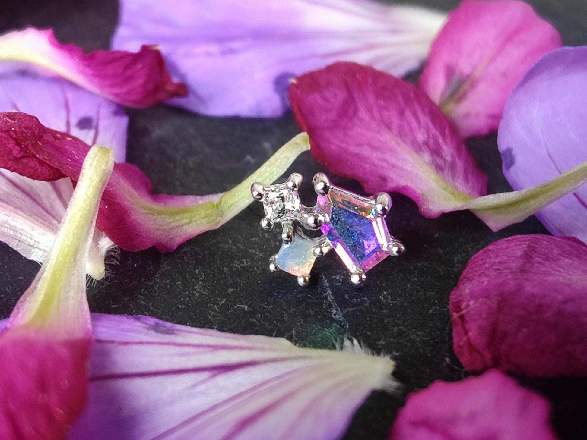 3 stones of different sizes connected by a gold setting. one in mercury mist topaz, one opal and one white cz.