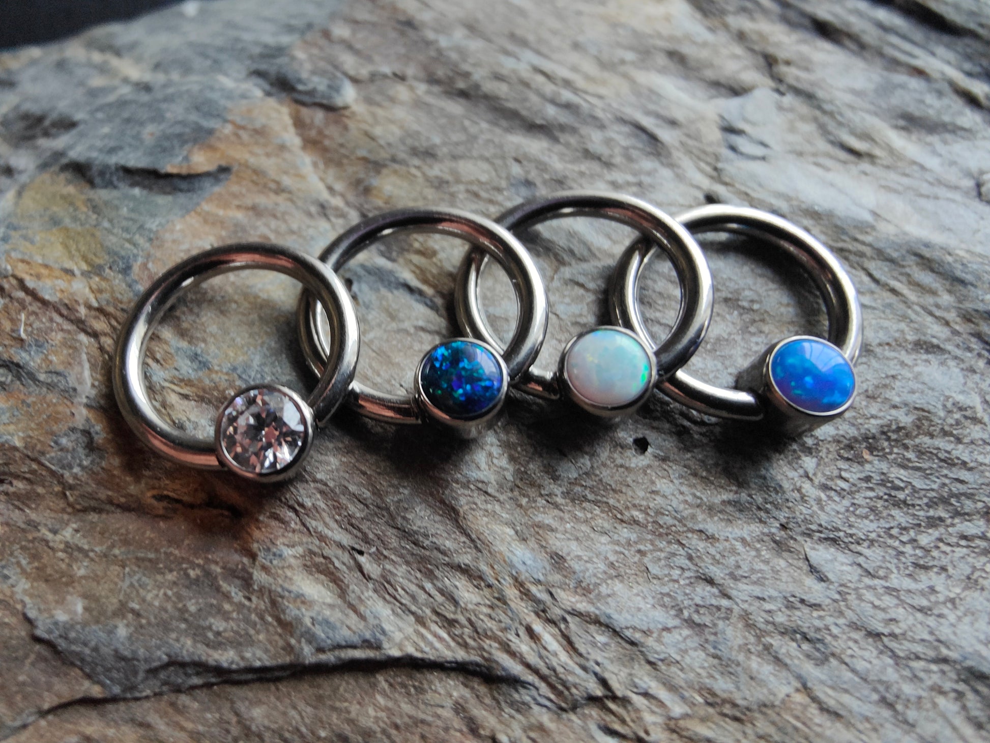 four niubium Ball clousre rings with a crystal, black opal, white opal and blue opal clip in