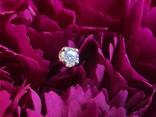 a genuine diamond prong set sat on a deep purple flower.
