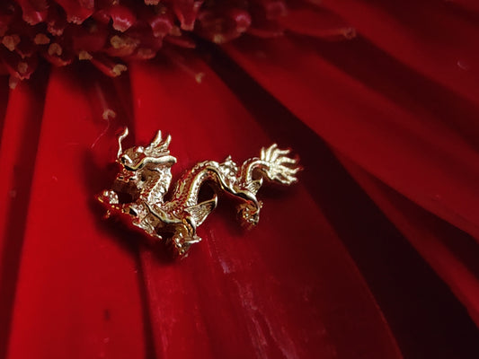 a yellow gold attatchment in the shape of a traditional chinese dragon. sat on a red flower
