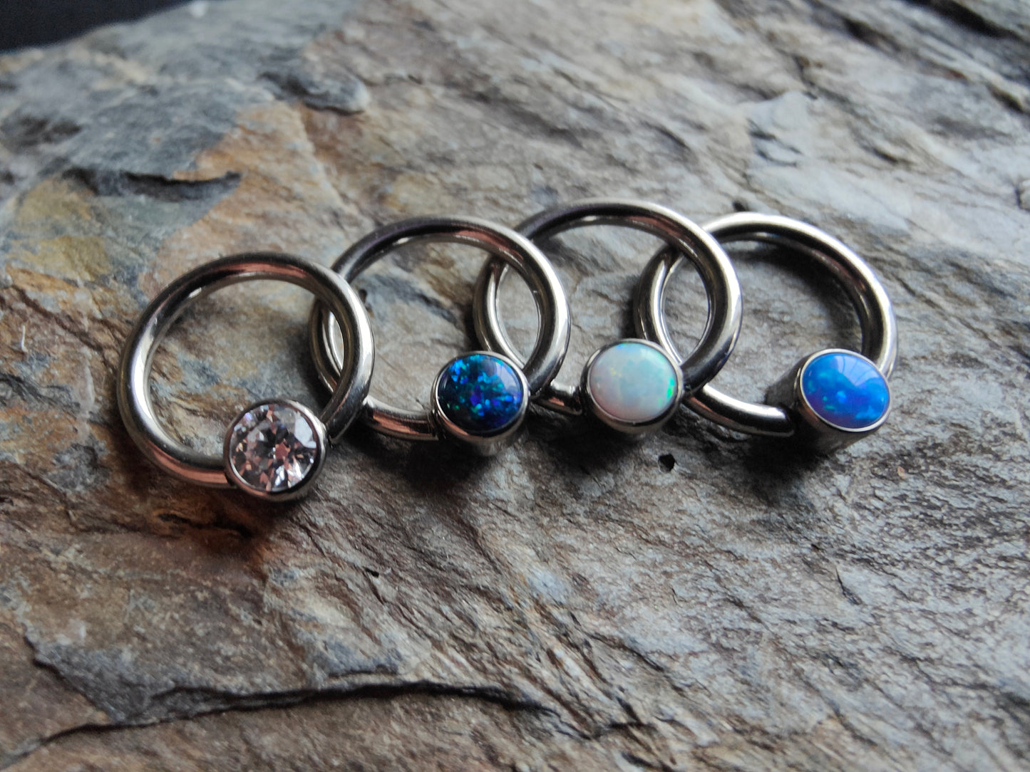 four niubium Ball clousre rings with a crystal, black opal, white opal and blue opal clip in