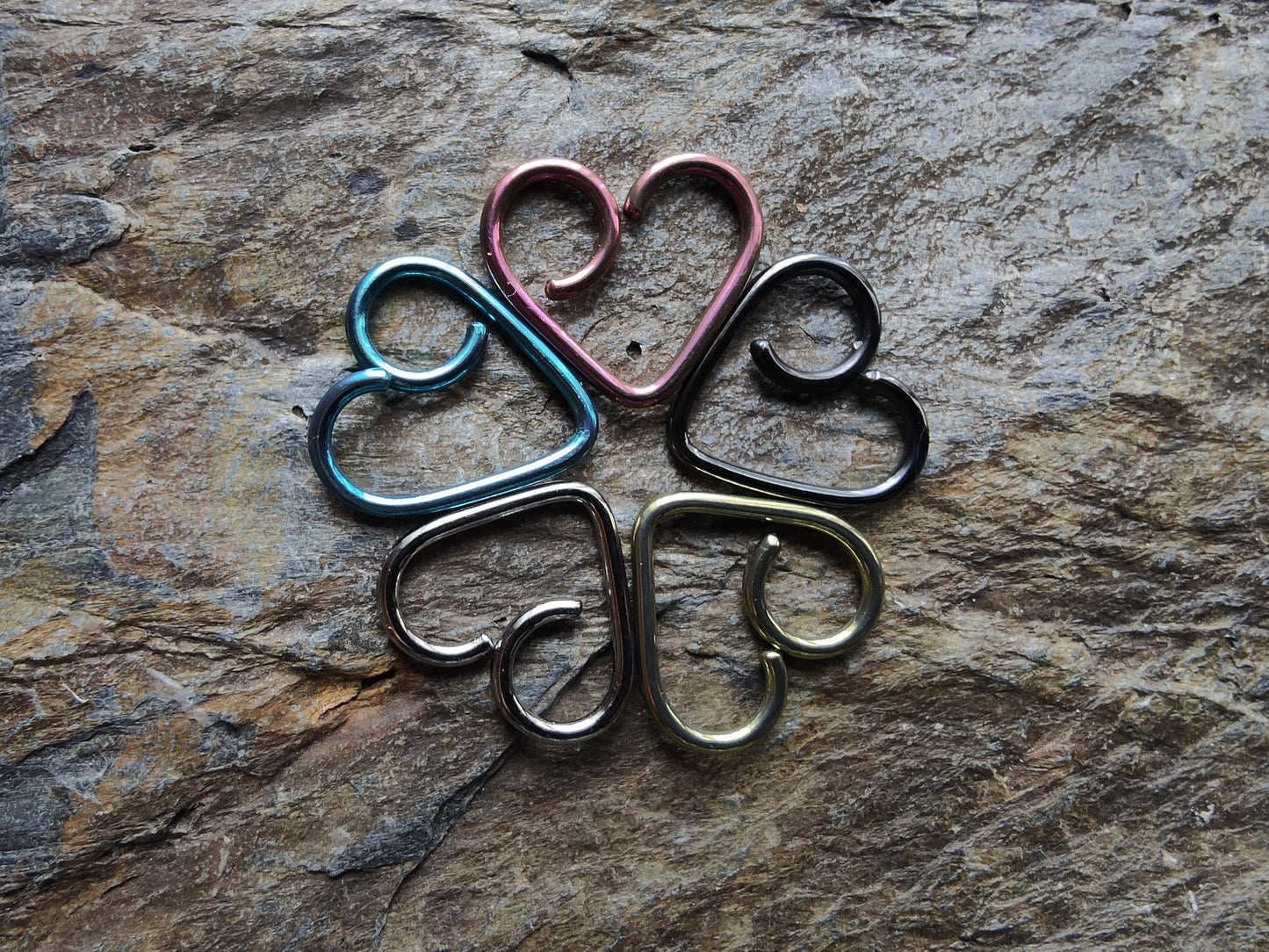 5 heart shaped rings coloured silver, blue, pink, black and gold